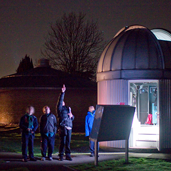 Students outside observatory at night