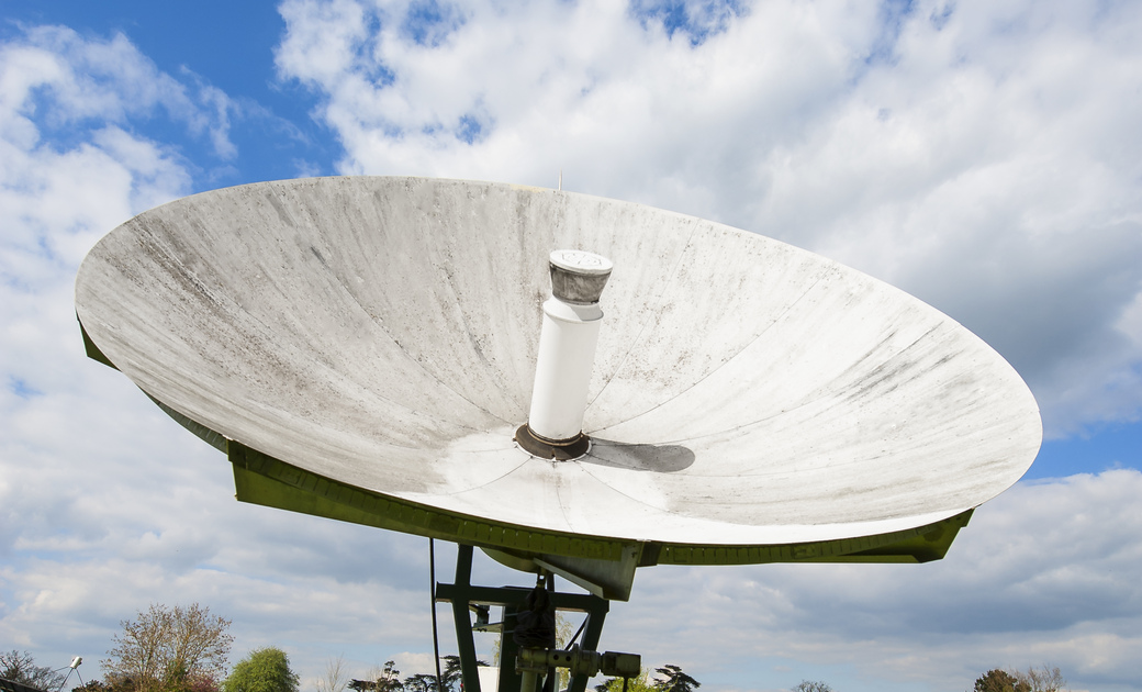 a large white radio telescope in the middle of Bayfordbury 