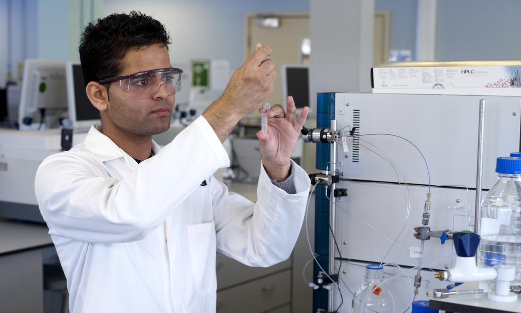 a male student working on an experiement and taking liquid from a vial