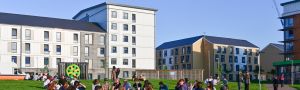 Image of student accommodation with students sitting on a lawn in front