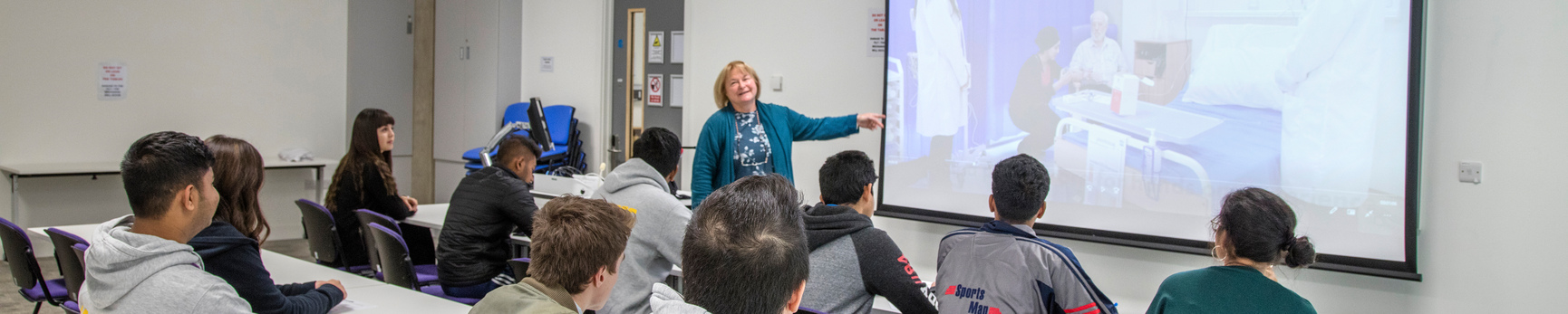 group pf students in class watching a tutor preset using a projector 