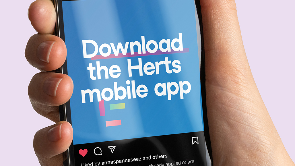 hand holding an iPhone, displaying a social media post by the university of hertfordshire