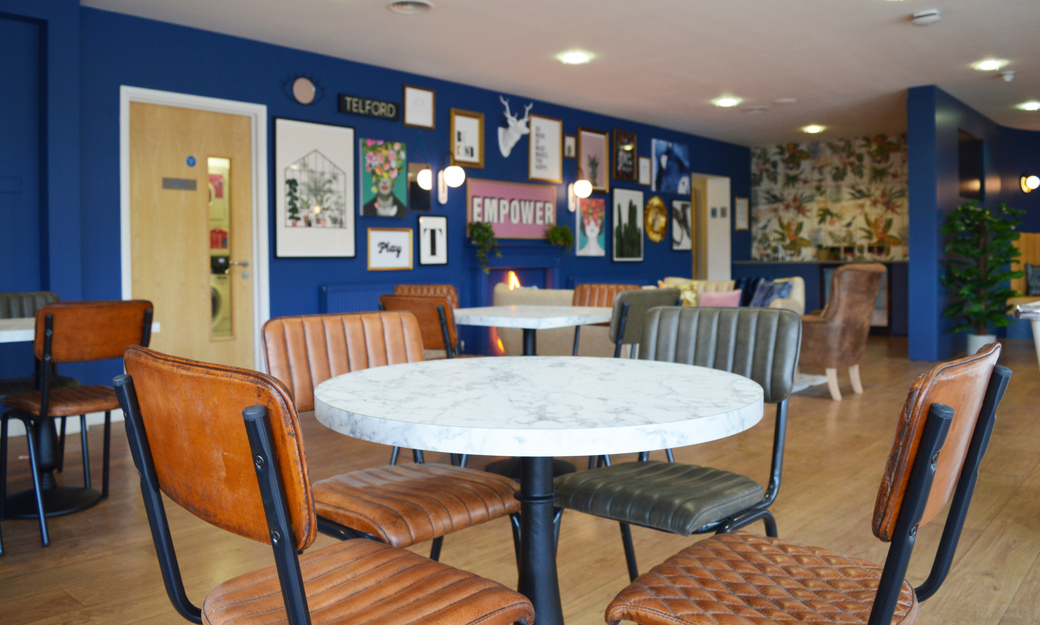 A common room showing tables, chairs, a sofa and wall decorations