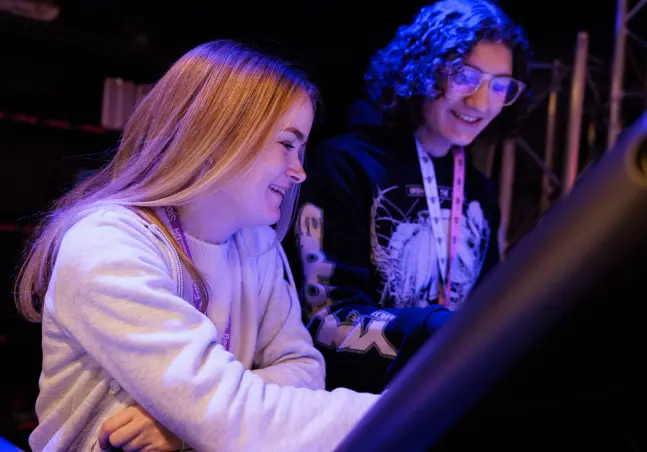 Two students smiling looking at a mixing deck