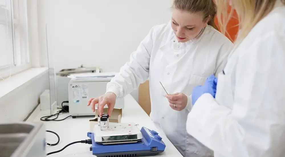 A lecturer in a lab coat explaining to a student