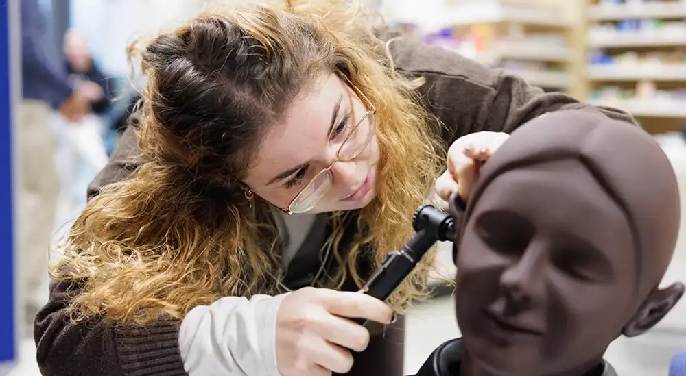 A student looking in a fake heads ear