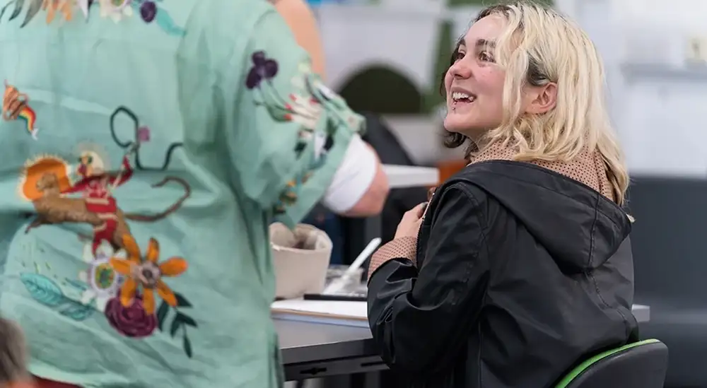 A student smiling and talking while sitting down