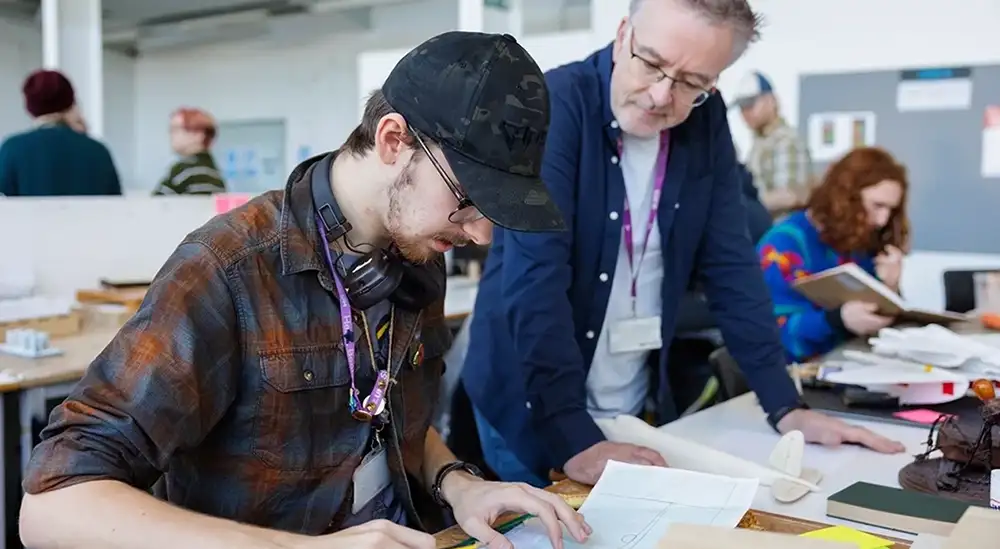 A student looking at their design work with a lecturer