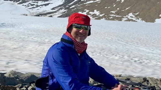 A person smiling sitting in a mountain range
