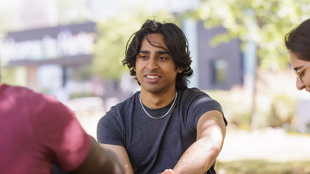 A student sitting down outside on a sunny day