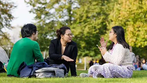 Three people sitting on grass
