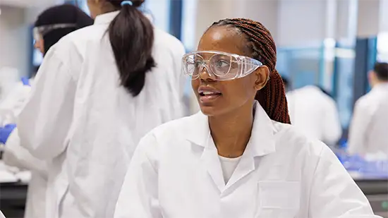 Student in a lab coat wearing safety goggles