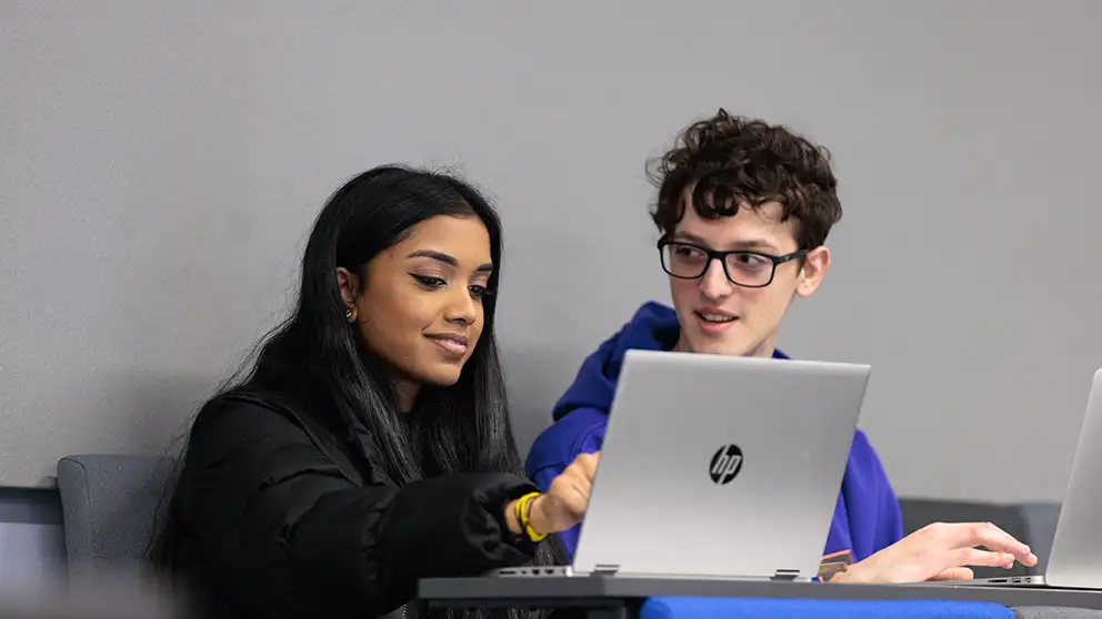 Two students looking at a laptop