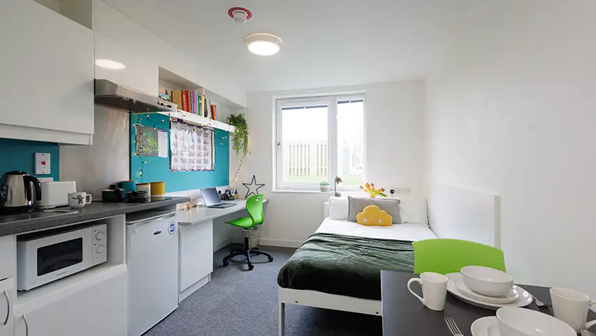 Waredrobe, bed, kitchen and desk with laptop