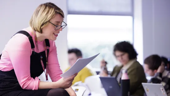 A lecturer talking to students from a paper
