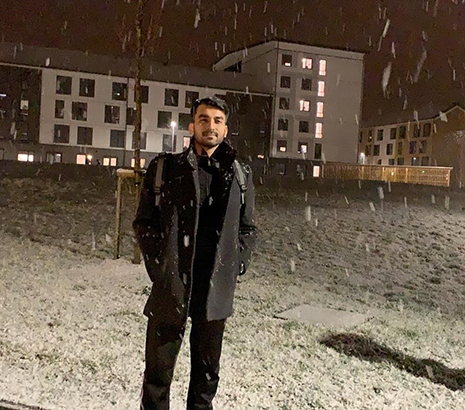 Syed Ali standing in the snow, wearing a black coat