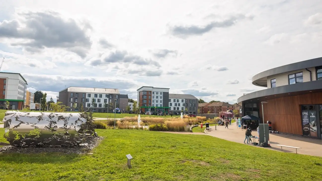 Outside image with the University campus in the background and a sculpture of artwork in the forground