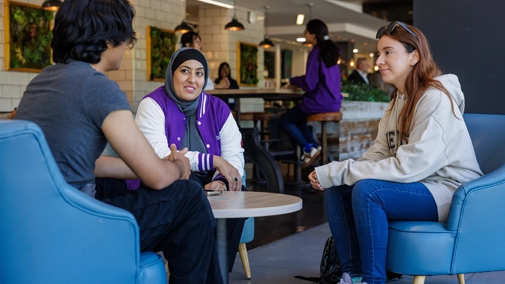 Three students sitting round a table chatting