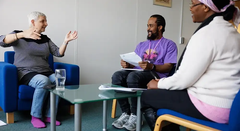 Three people round a table talking 