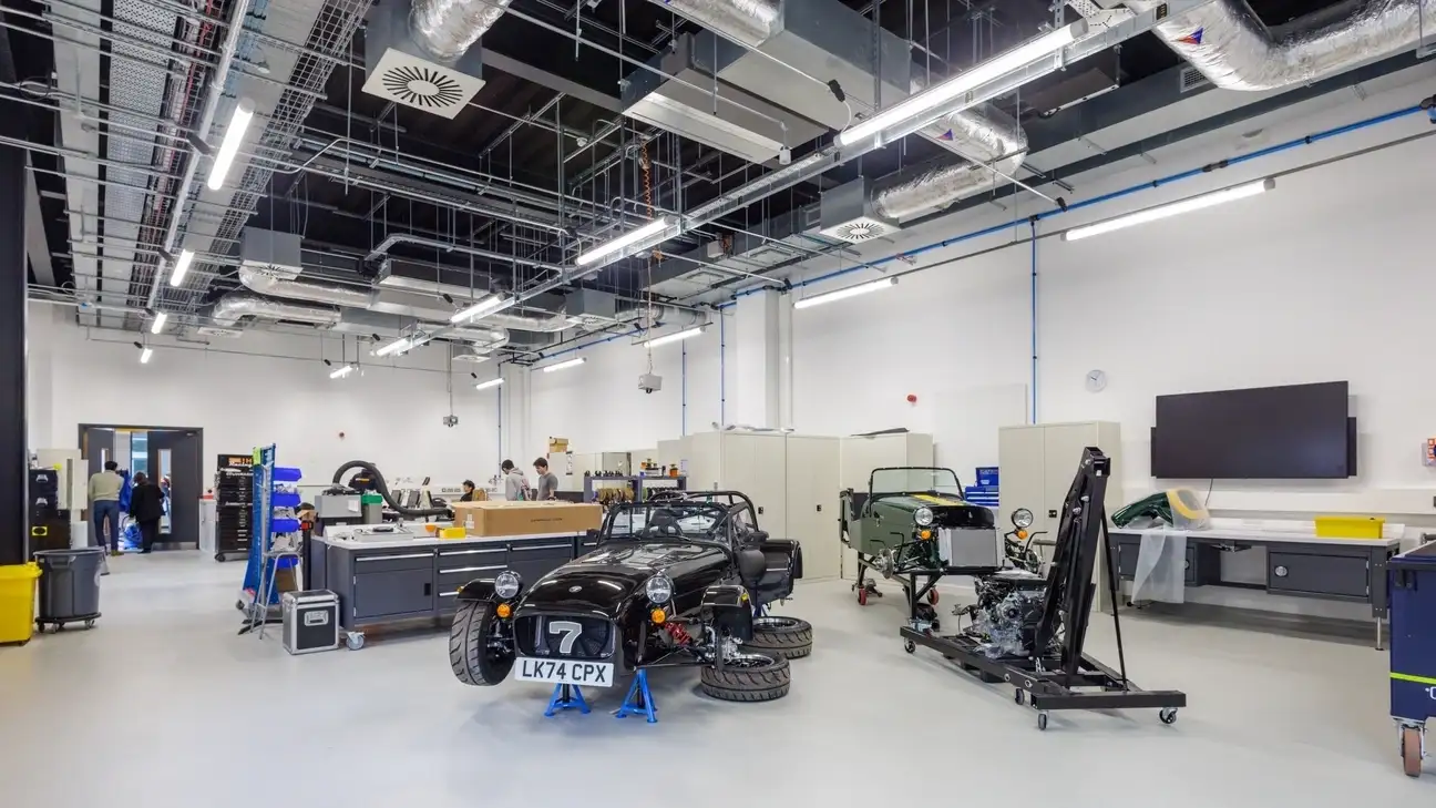 A workshop with a car on jack and wheels missing