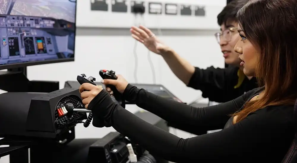 A lecturer talking to a student using a flight simulator