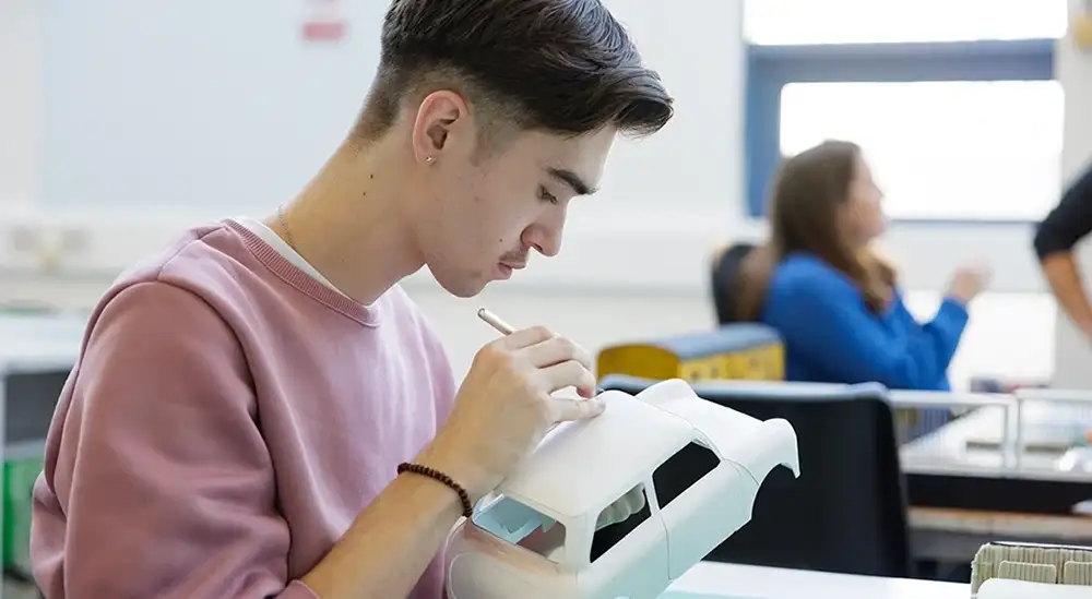 A student drawing on a model car