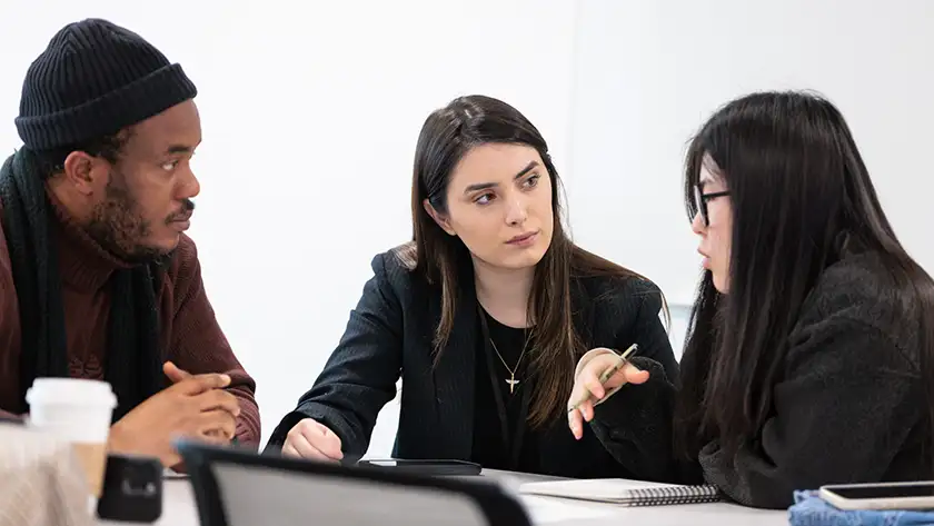 Three students sitting round a table working together