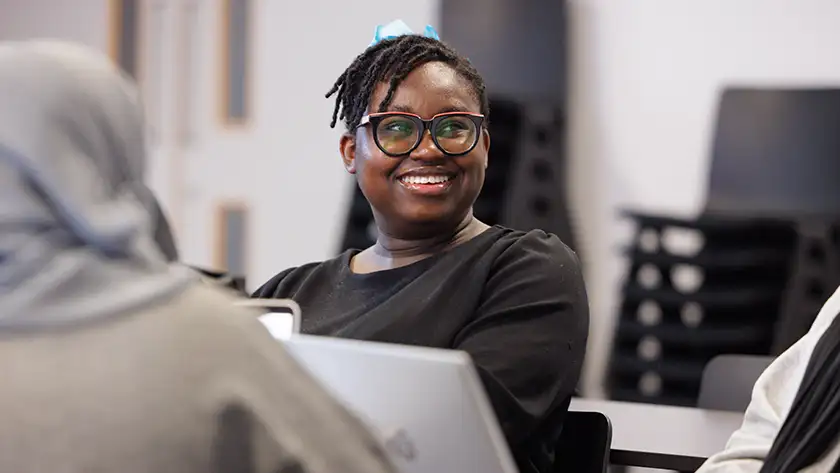A student relaxing on a chair smiling with peers