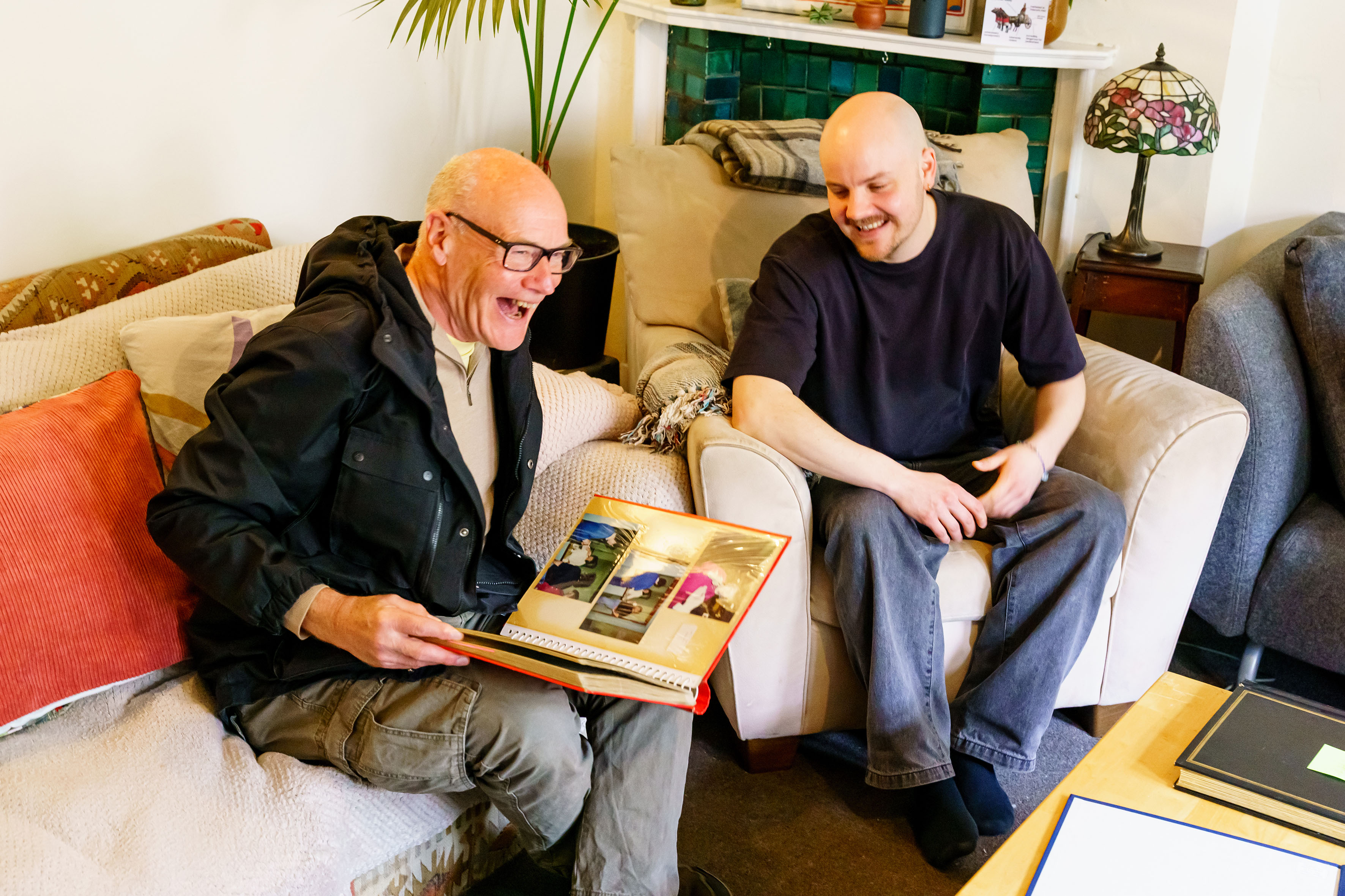 Two white men sitting on a sofa laughing together