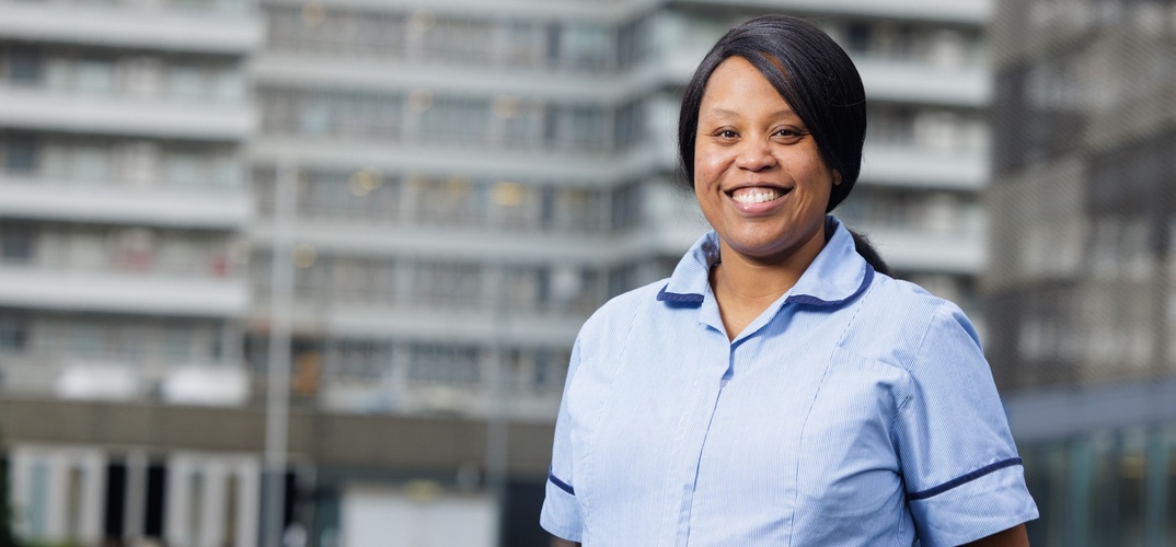 Gloria Sikapite in her nurses uniform focused against a blurred city landscape
