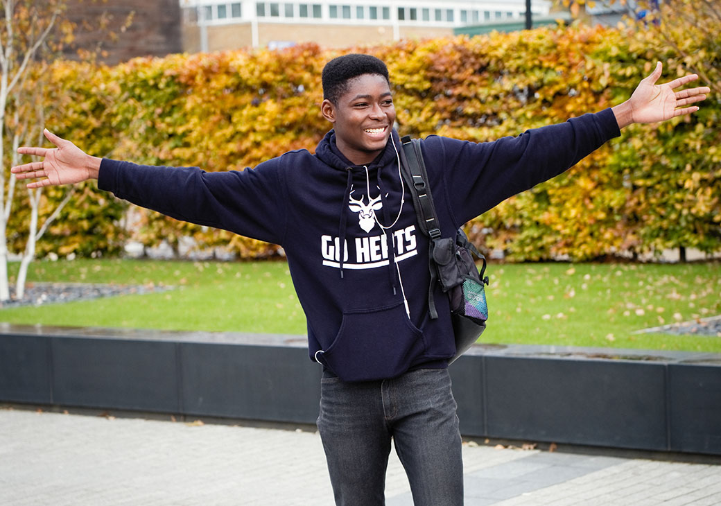Black male student celebrating in Herts hoodie
