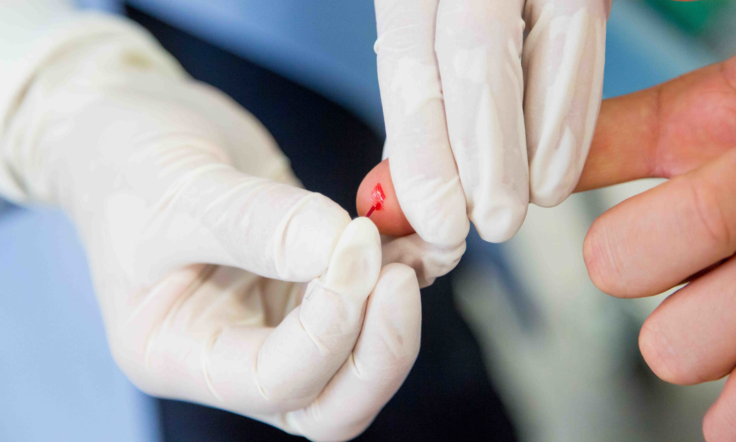 Doctor pricking patient finger for blood