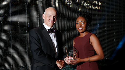 A member of staff from our BAME community, smiles as she collects her award from Quintin McKellar