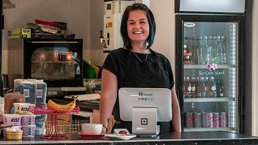 Owner of small cafe in Herts standing behind counter