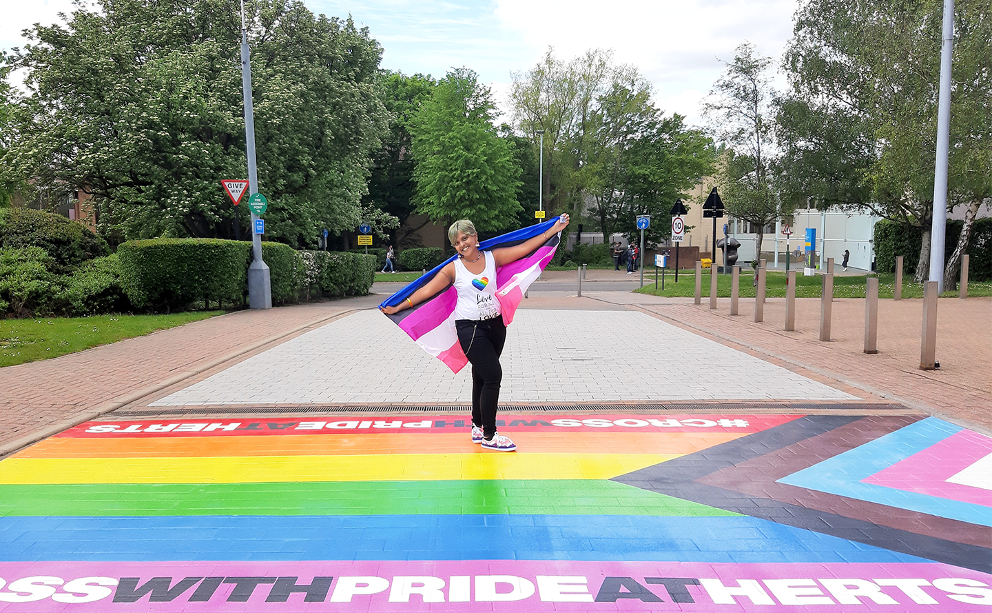 Student proudly showcasing the LGBT+ flag that is printed on the floor