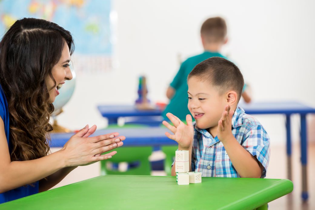 a student with a patient completing an activity. they are both clapping and smiling.