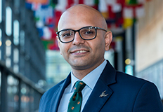 Subal Kaushik, standing in front of international country flags