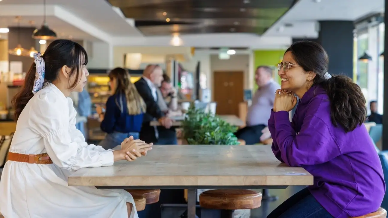 Two students sitting down at a table talking