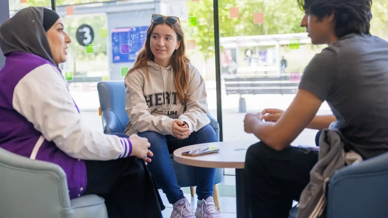 Three students sitting round a table chatting