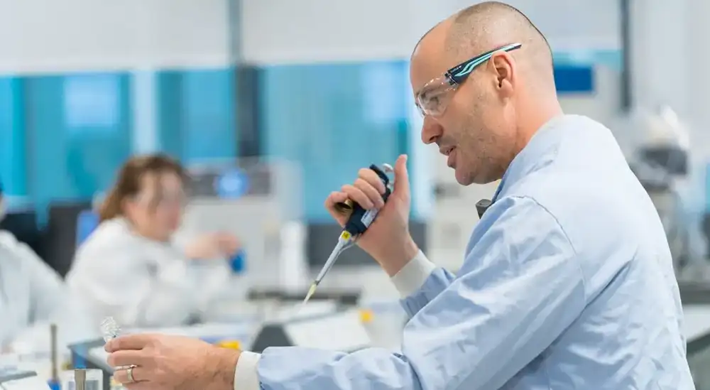 A student in lab coat with a pipet 