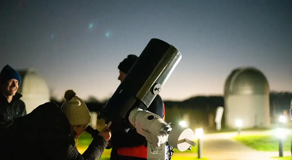 Students looking through a small telescope outside
