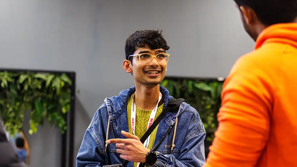 Student wearing glasses talking to a peer