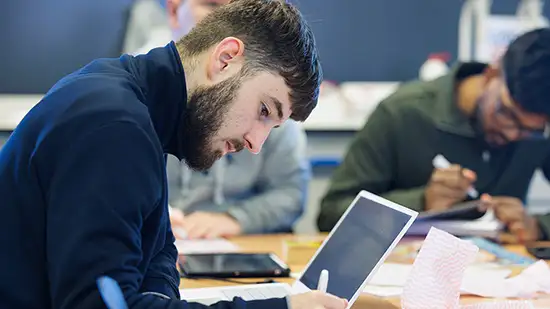 Student sitting at a table in front of a laptop