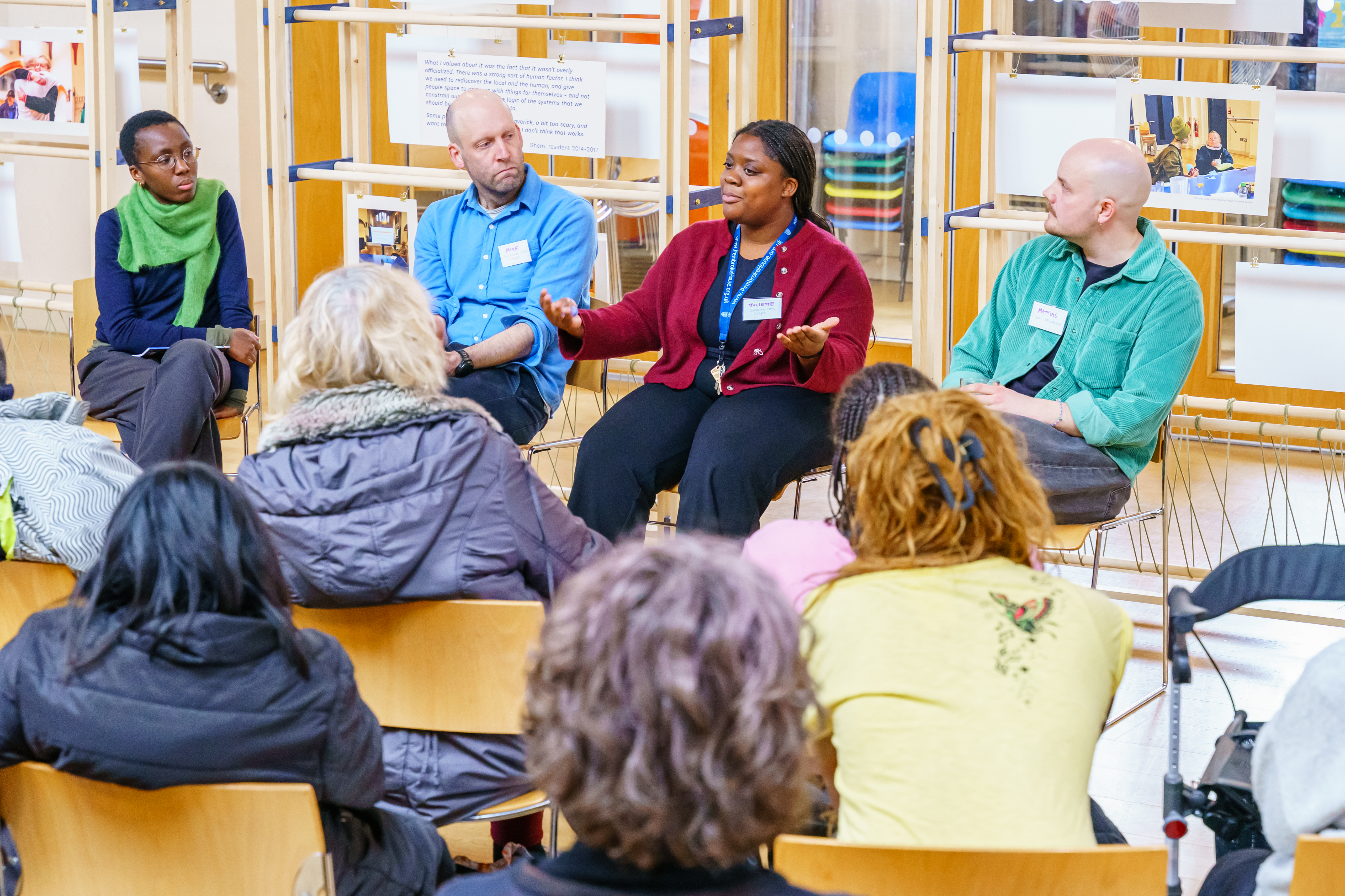 A black woman presents to a crowd alongside two white men and another black person 