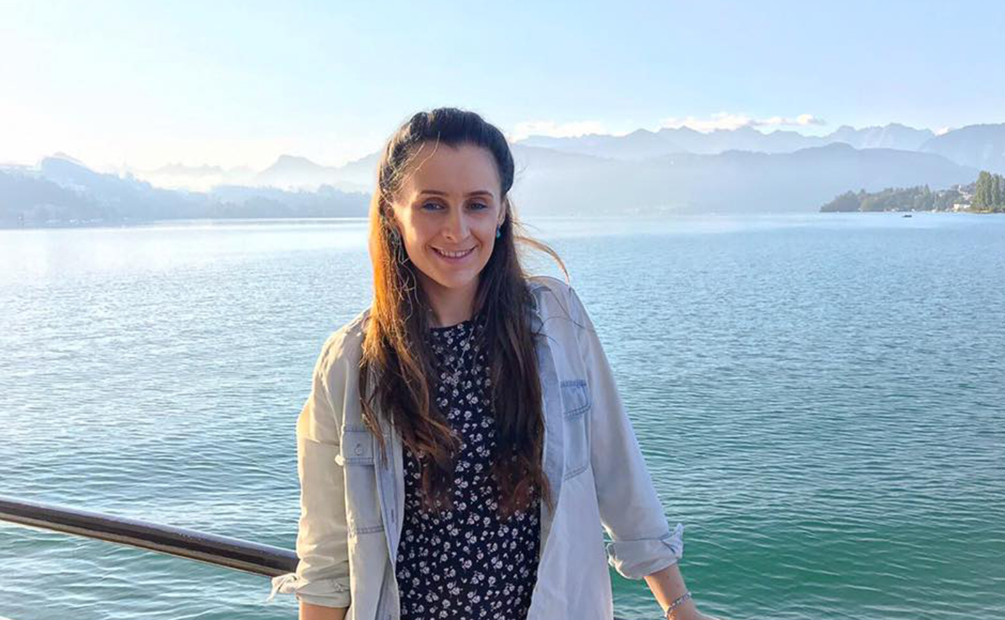 Anna stands in front of a blue sea on a sunny day