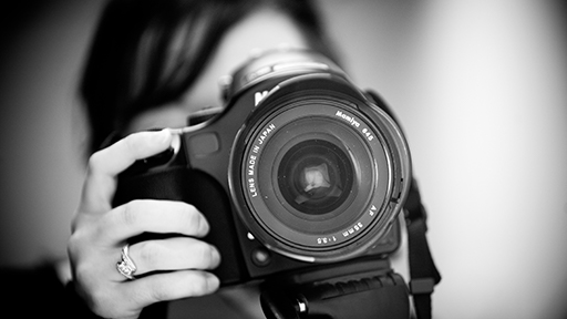 a black and white photograph of female hands holding a camera