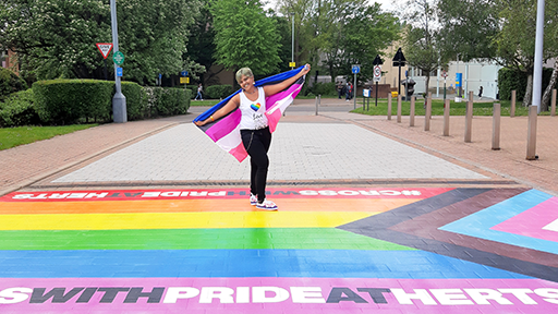 Student proudly showcasing the LGBT+ flag that is printed on the floor