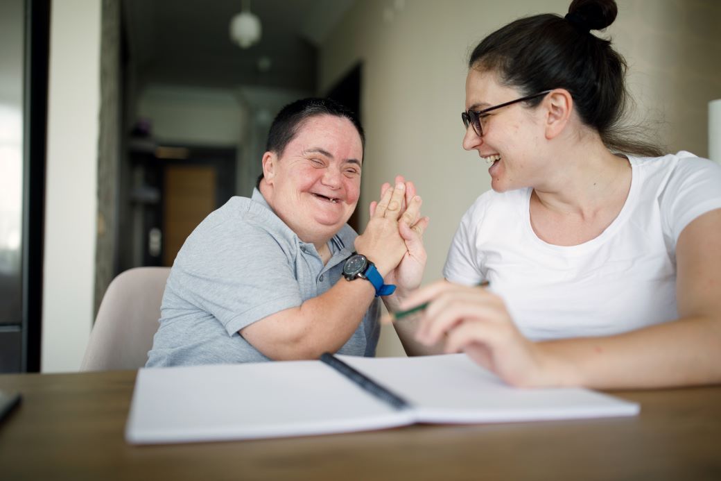 a student and a patient high fiving after completing an activity. they are both smiling