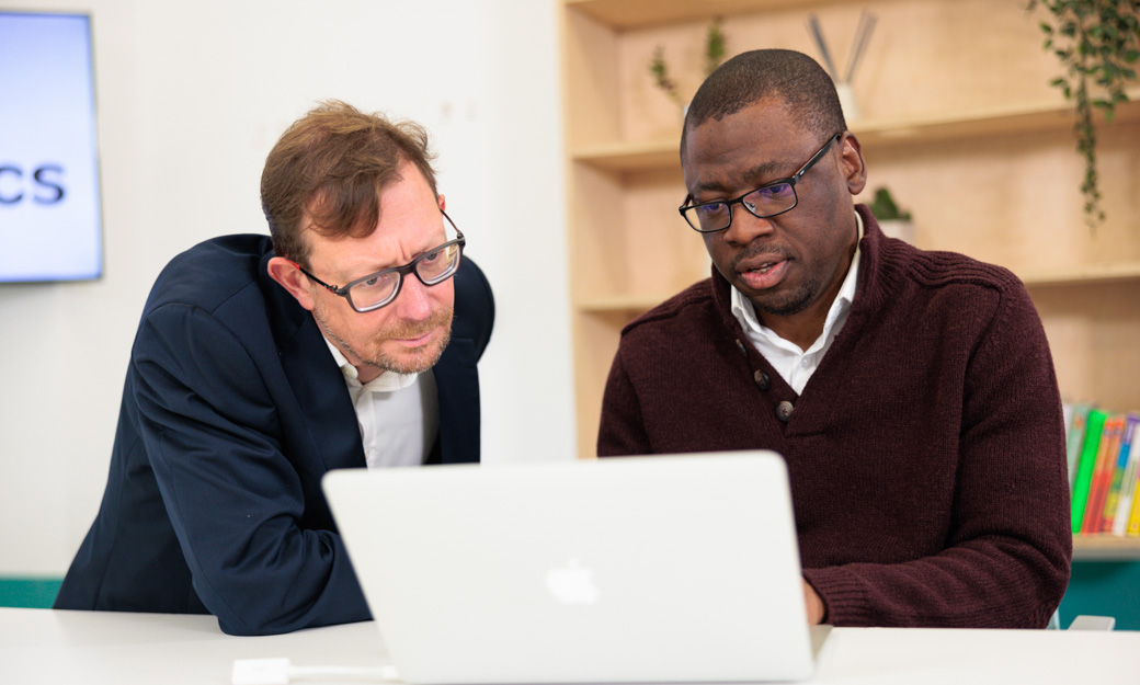 Sola and a male colleague looking at a laptop