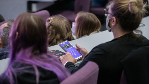 Student holding mobile phone during a lecture